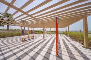 Ein Außenbereich zum Trainieren mit Schachbrettmuster-Boden, Fitnessgeräten und einer Pergola.