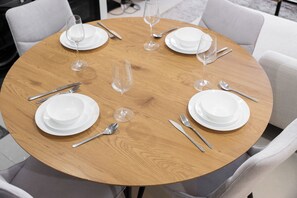 A round wooden table set for six with white plates, cutlery, and wine glasses. - StayShort - Tranquil 1BR Hideaway in Damac Hills! (Damac Hills A)