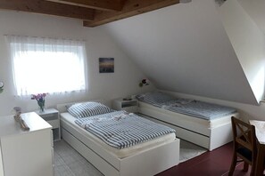 Ein Schlafzimmer mit zwei Betten, einem Nachttisch, einem Stuhl und einem Fenster mit Vorhängen.