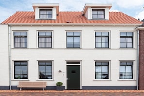 A two-story building with a white facade, multiple windows, and a black door.