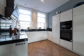 A modern kitchen with white cabinets, a black countertop, and a built-in oven.