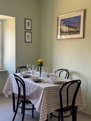 A dining table set with plates, glasses, and a vase with yellow flowers, surrounded by chairs. - BREAD AND TULIPS - a cozy vacation home with a view of Rocca Calascio (Castelvecchio Calvisio)