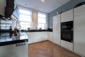 A modern kitchen with white cabinets, a black countertop, and a built-in oven.