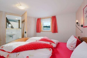 Une chambre à coucher avec un lit, une fenêtre avec des rideaux, une lampe de chevet et un miroir.