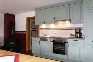 Une cuisine avec des meubles de couleur vert clair, une cuisinière, un four et une machine à café.