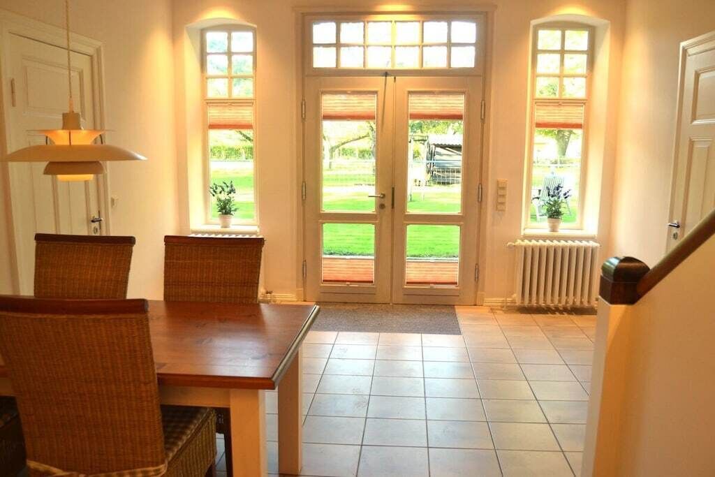 A dining area with a table and chairs, a double door with glass panels, and a view of the outdoors.