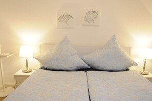 A double bed with two pillows, a bedside table with a lamp, and wall art. - Holiday apartment with 2 bedrooms (Lübeck)