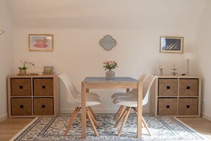 A dining area with a wooden table and chairs, a patterned rug, and two sideboards with baskets. - Holiday apartment with 2 bedrooms (Lübeck)