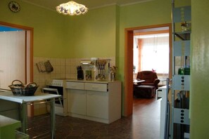 Eine kleine Küche mit Herd, Backofen und weißen Schränken. Ein Essbereich mit Stuhl und Tisch ist ebenfalls vorhanden.