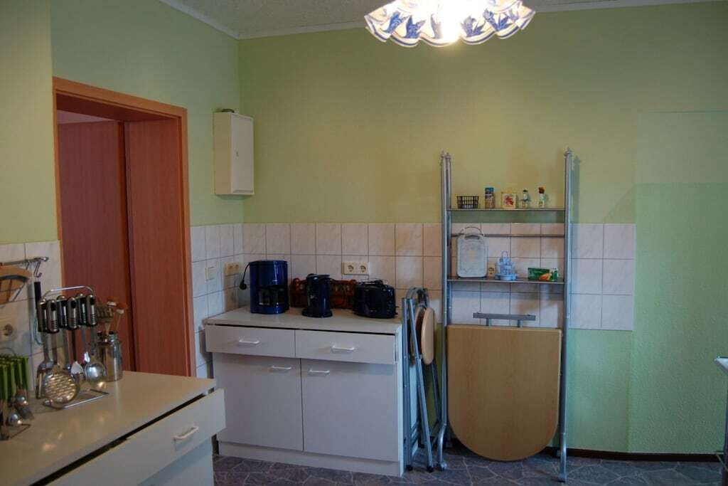A compact kitchen with a white countertop, a coffee maker, and a metal rack.