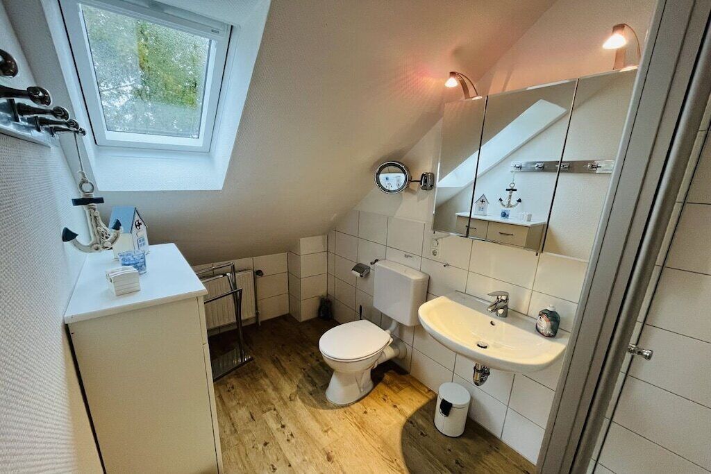 A compact bathroom with a toilet, sink, and a mirror.