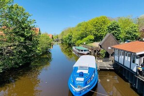 A narrow waterway with a blue boat docked on the right, surrounded by greenery and buildings. - Apartment in Otterndorf with swimming pool (Otterndorf)