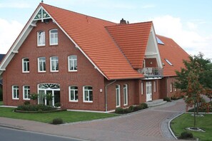 Een gebouw van rode baksteen met een steile dakschild, veel ramen en een hekwerk.