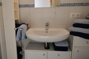 Een badkamer met een wit wastafel, een spiegel en een handdoekrek.