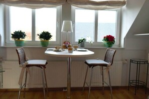 Een eetgedeelte met een ronde tafel, twee stoelen, een lamp en potplanten.