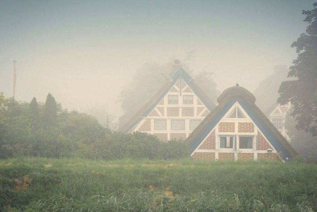 Una casa con un tetto spiovente e una facciata simmetrica, immersa nel verde.