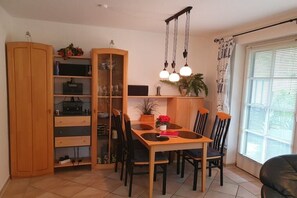 Ein Essbereich mit Holztisch und -stühlen, einem Schrank mit Glastüren und einer Hängeleuchte.