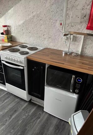 Una cocina compacta con estufa, horno, microondas y encimera de madera.