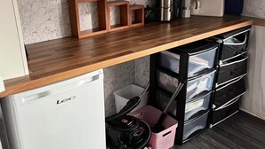 Una cocina compacta con encimera de madera, un refrigerador blanco y un mueble de almacenamiento negro con cajones.