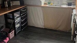 Cocina compacta con encimera de madera, horno integrado y ventana con vistas al exterior.