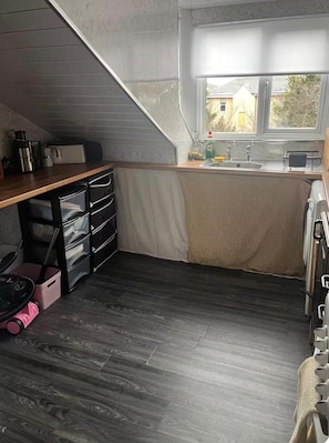 A compact kitchen with a wooden countertop, a built-in oven, and a window providing a view of the outside.