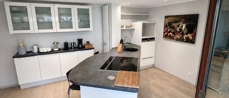 A modern kitchen with a central island, white cabinetry, and a painting on the wall.