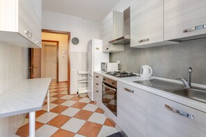 Une cuisine de taille réduite avec un carrelage à motifs, un évier, une cuisinière et des placards.