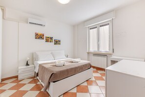 A hotel room with a bed, a bedside table, a lamp, a window with curtains, and artwork on the wall. - Zip House Apartment Verona (Verona)