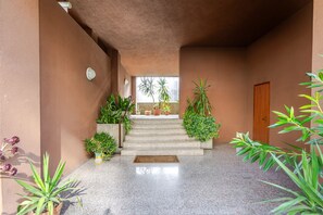 A covered outdoor area with a set of stairs leading to a door, surrounded by potted plants and a tiled floor. - Zip House Apartment Verona (Verona)