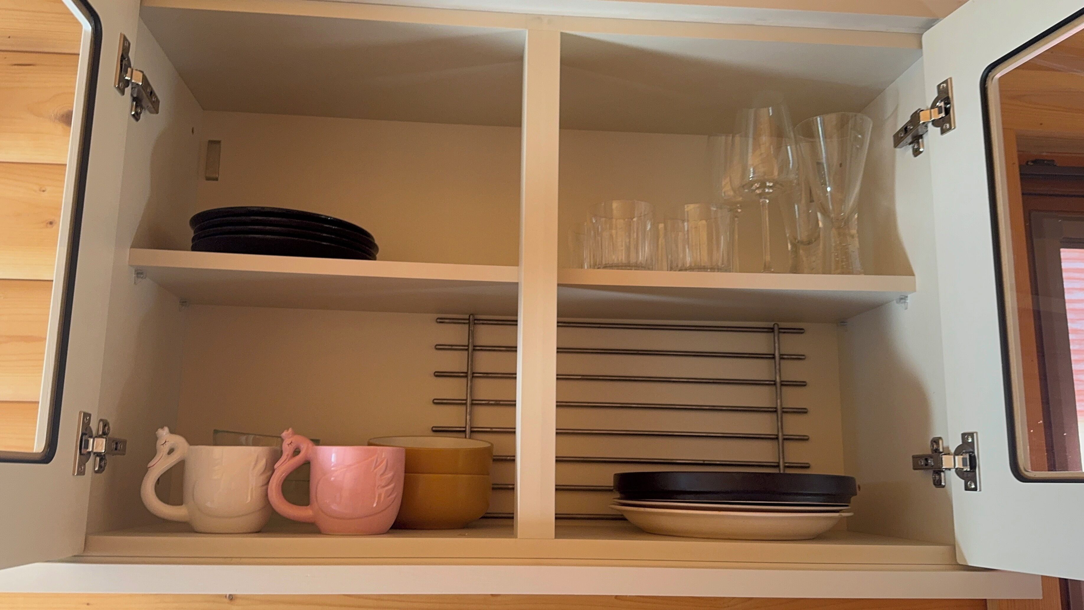 A cabinet with shelves containing plates, cups, and glasses.