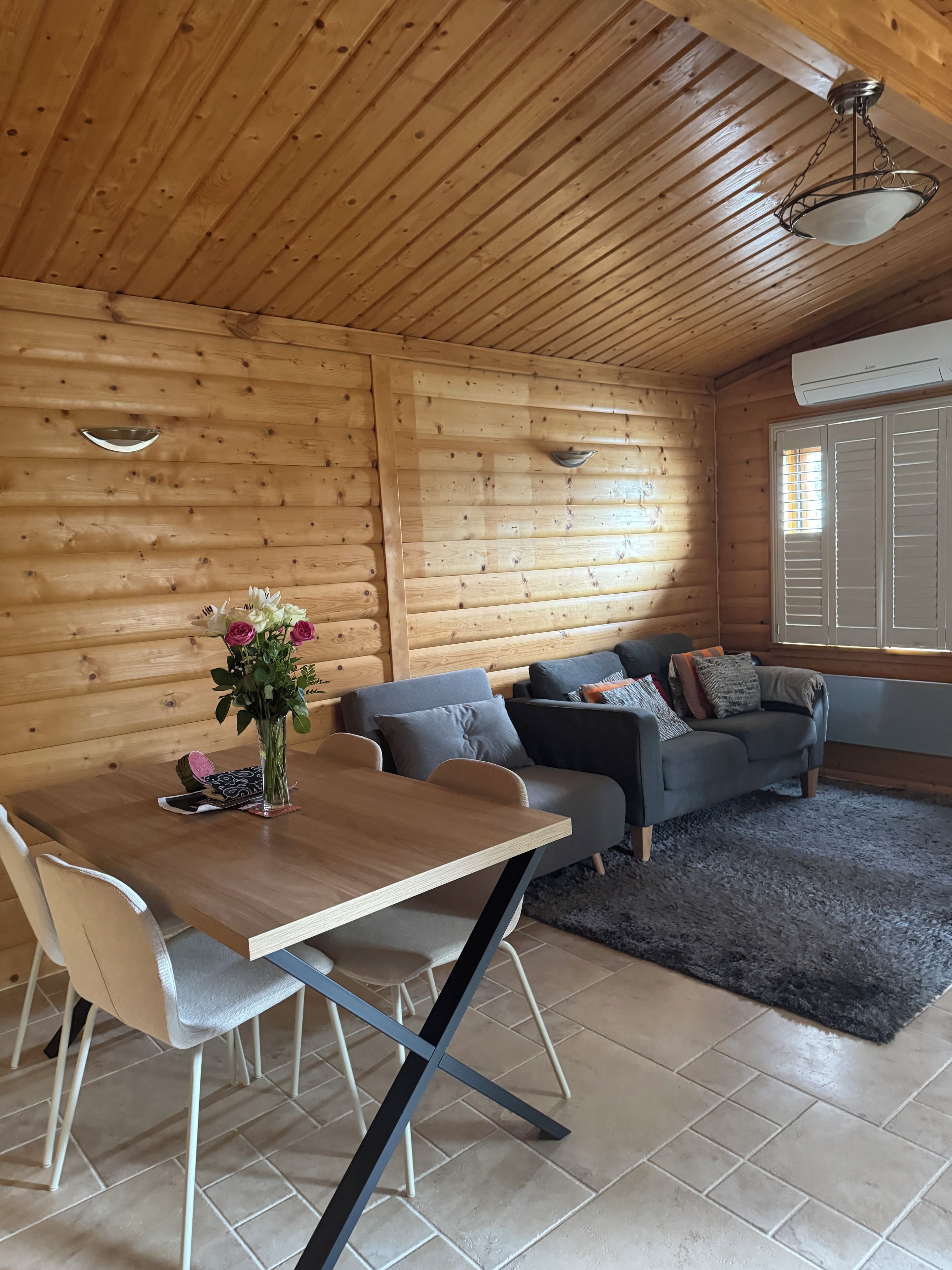 Un interior de madera con una mesa de comedor, sillas, un sofá y un jarrón decorativo.