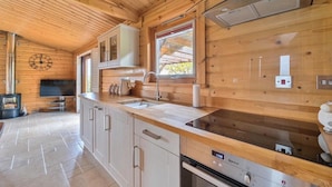 Eine moderne Küche mit Holzschränken, einem eingebauten Backofen und einem Fenster mit Aussicht.