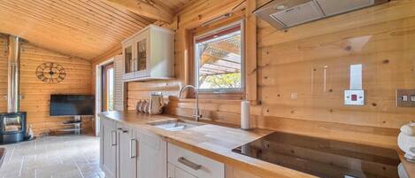 A modern kitchen with wooden cabinetry, a built-in oven, and a window with a view.