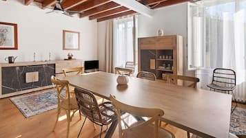 Un'ampia sala da pranzo con un lungo tavolo in legno, sedie in vimini e una libreria a muro.