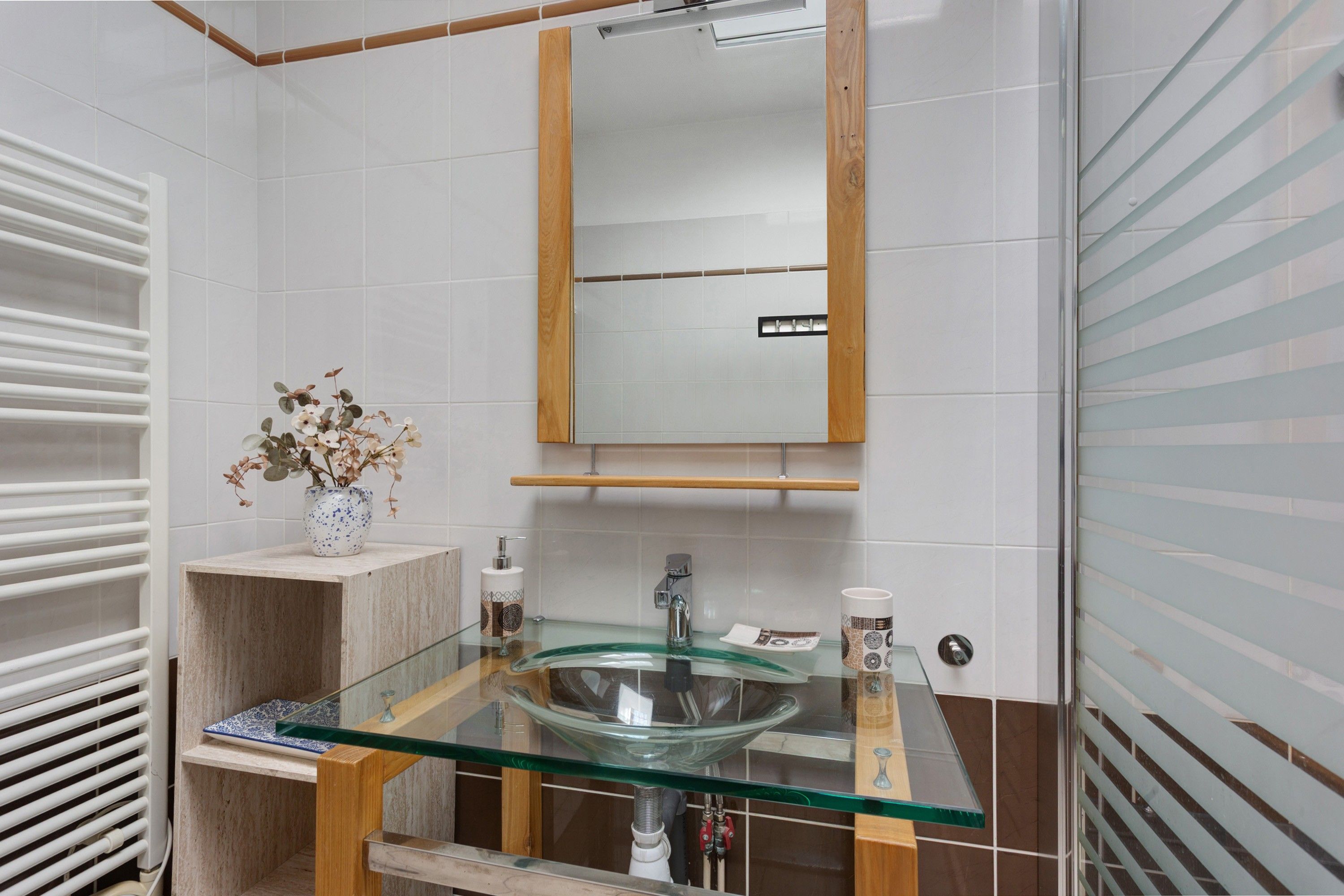 Une salle de bain avec un lavabo en verre, un meuble-lavabo en bois et un miroir.