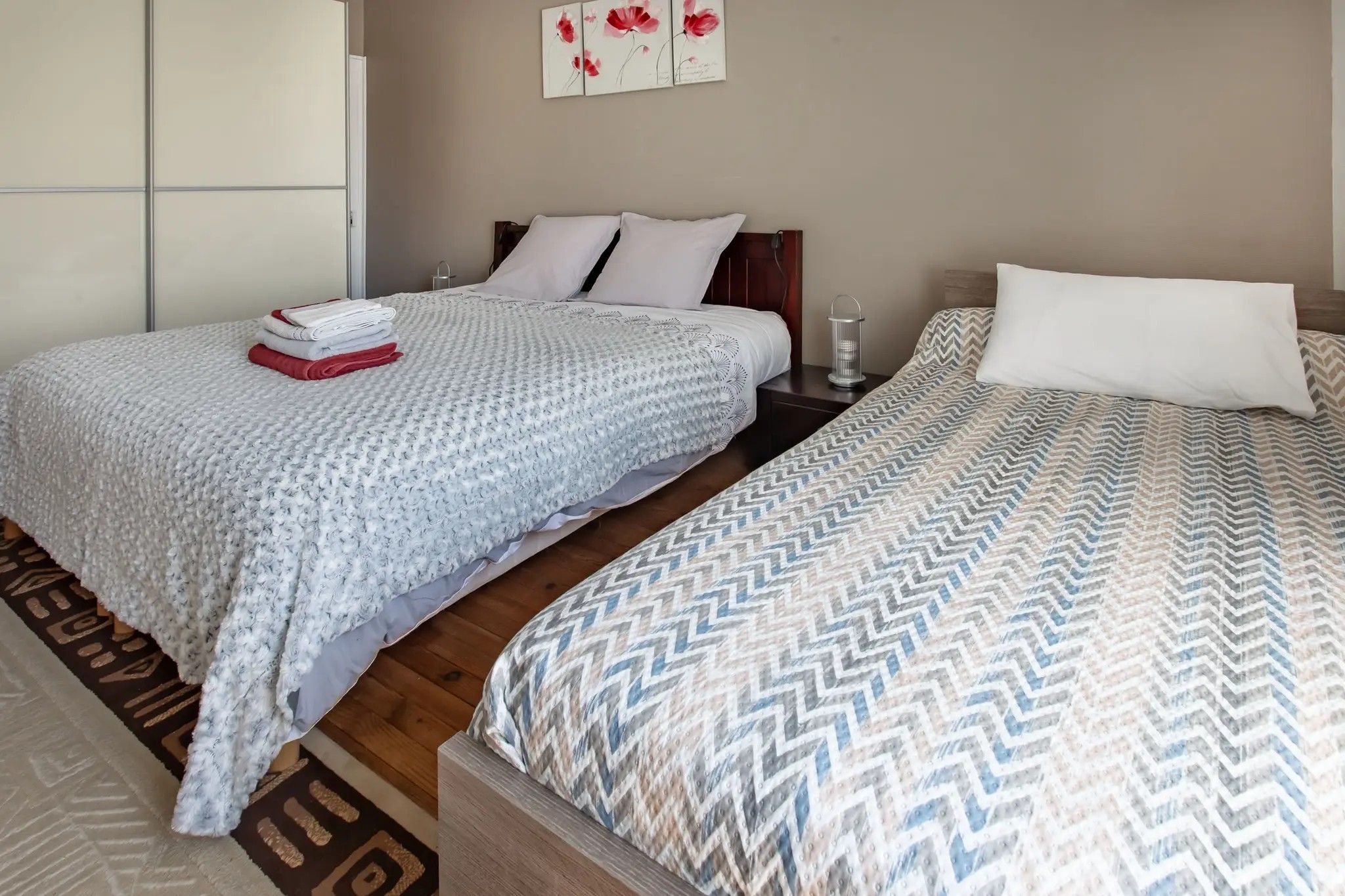 Une chambre d’hôtel avec deux lits, une table de chevet, une lampe et une œuvre d’art accrochée au mur.