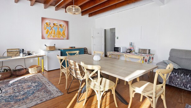 A dining area with a wooden table and chairs, a kitchen area with a microwave and stove, and a sofa.