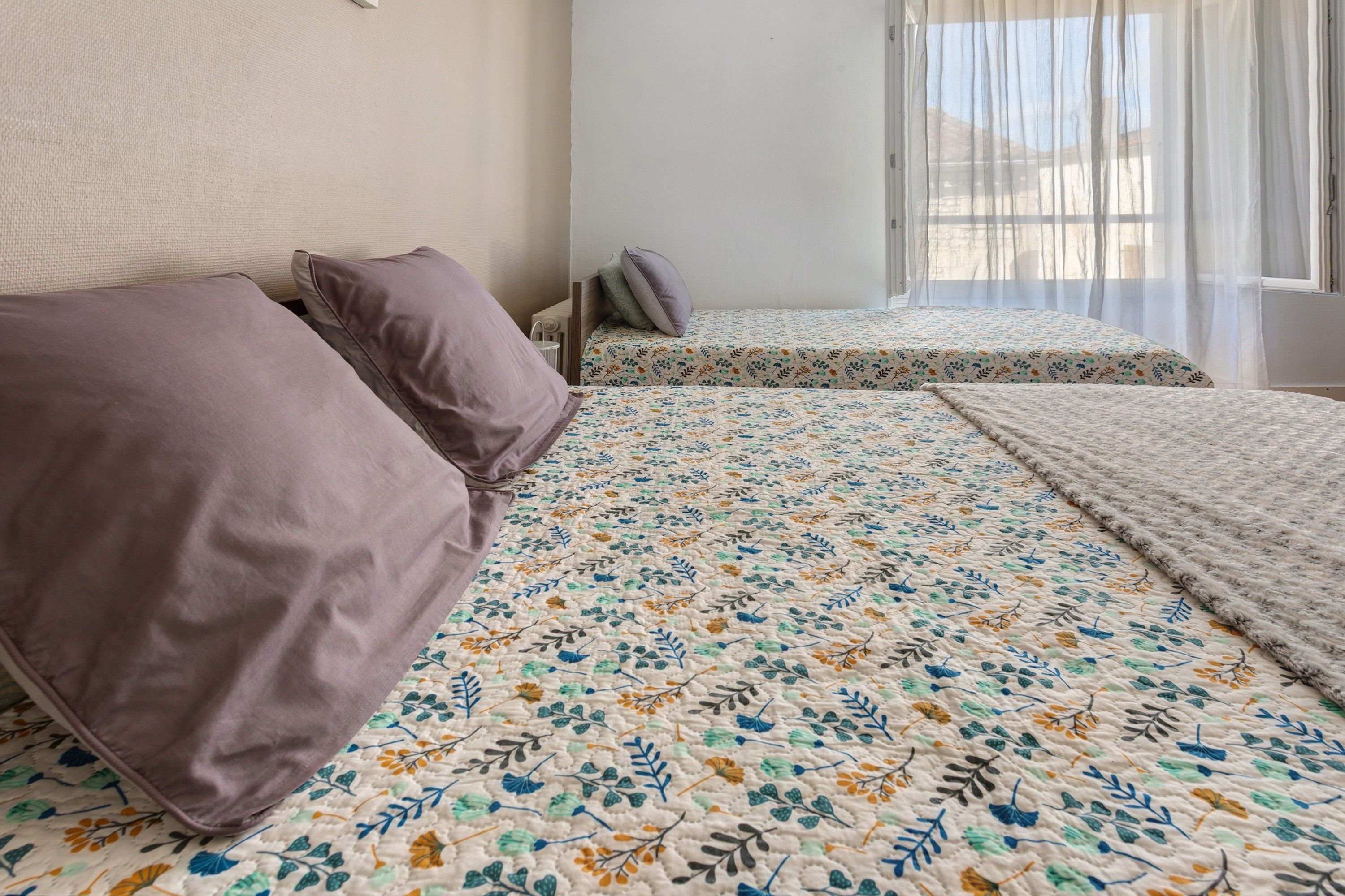 Een kamer met twee bedden, elk met een bloemenprint dekbed.