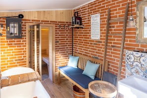 A rustic bathroom with a wooden bench, a bathtub, and a sign in German.