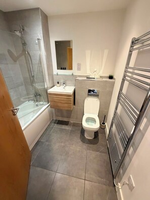 A compact bathroom with a glass shower enclosure, a sink with a mirror, and a toilet. - Hearth Residences - A perfect Home for Your Stay (Coventry)