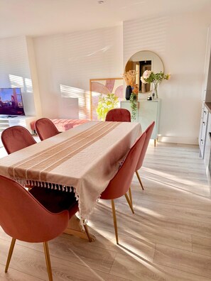 A dining area with a long table, red chairs, and a light-colored tablecloth. - Hearth Residences - A perfect Home for Your Stay (Coventry)
