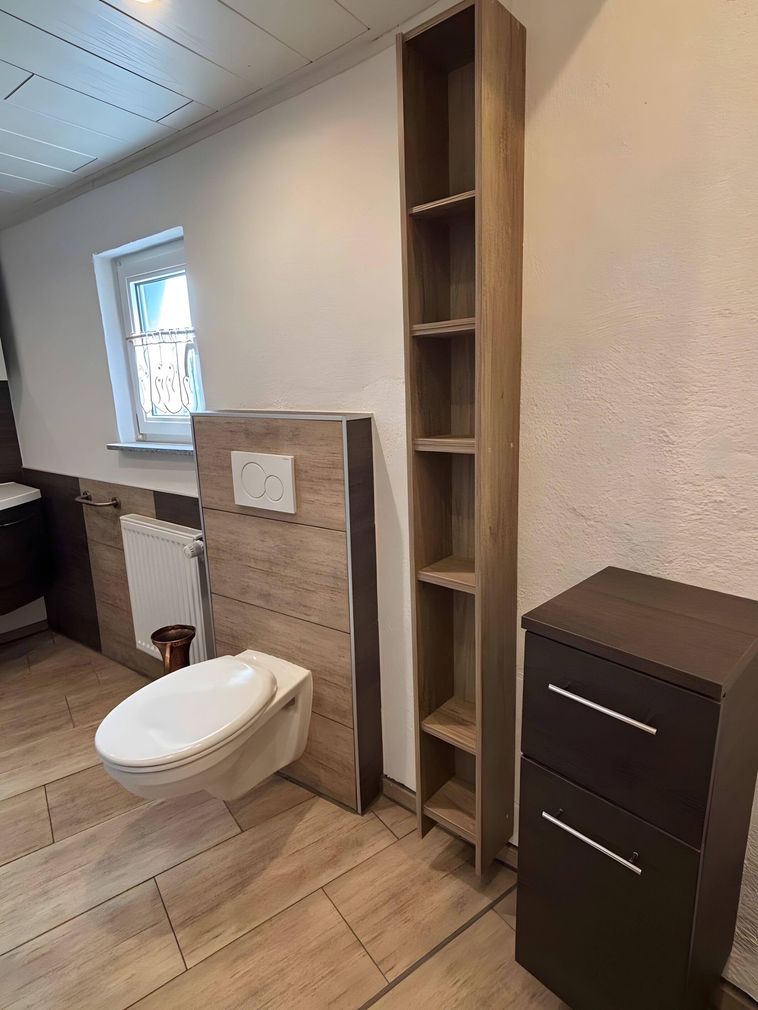 A bathroom with a toilet, a wooden cabinet, and a radiator.