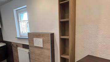 A bathroom with a toilet, a wooden cabinet, and a radiator.
