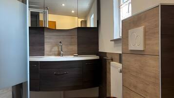 Une salle de bain moderne équipée de toilettes, d’un lavabo et d’un miroir.