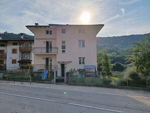 Un edifici residencial de diverses plantes amb un balcó, una escala i una entrada petita.
