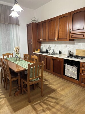 A kitchen with wooden cabinets, a dining table with chairs, and a stove. - SICILIA NEL CUORE APARTMENT is located in Cassibile, just 3 minutes from the beach! (Cassibile)