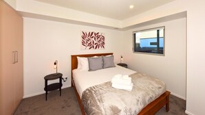 A hotel room with a bed, bedside tables, a window, and a wall art piece. - The Cosy Nook for a Relaxing City Stay (Christchurch)