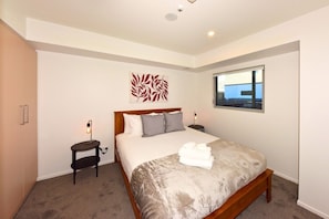 A hotel room with a bed, bedside tables, a window, and a wall art piece. - The Cosy Nook for a Relaxing City Stay (Christchurch)