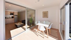 A modern interior with a dining area, kitchen, and sliding glass doors leading to an outdoor space. - The Cosy Nook for a Relaxing City Stay (Christchurch)