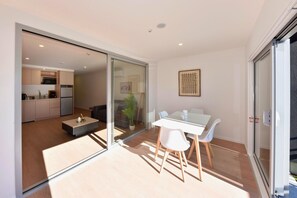 A modern interior with a dining area, kitchen, and sliding glass doors leading to an outdoor space. - The Cosy Nook for a Relaxing City Stay (Christchurch)